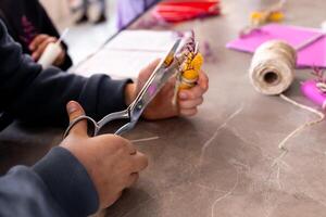 Young caucasian child crafting with scissors and yarn on a table photo