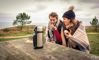 A man and woman sitting at a picnic table with a cup of coffee photo