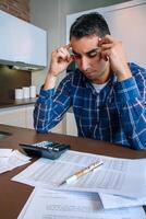 Man with calculator and papers in kitchen photo