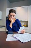 A woman is sitting at a table with a calculator and papers photo