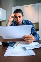Man with papers and calculator at home photo