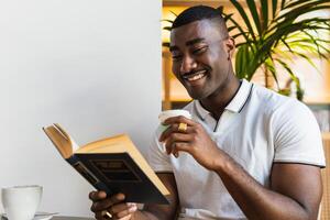 A smiling man is reading a book while sitting at a table photo