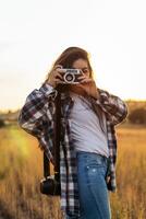 A woman taking a photo with a camera in a field