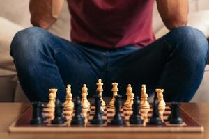 A man sitting on a couch with a chess board. photo