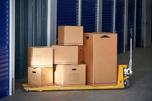 A man is standing in front of a storage unit with boxes on a dolly photo