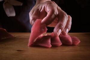 A person cutting up raw meat on a wooden table photo