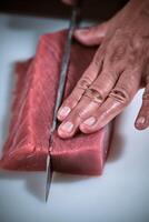 A person cutting up a piece of raw meat with a knife. A chef showing his knife skills photo