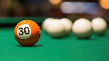 An orange billiard ball with the number 30 on a green felt table. photo