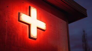 Illuminated red cross sign on a building at night. photo