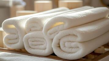 A stack of neatly rolled white towels on a wooden tray. photo