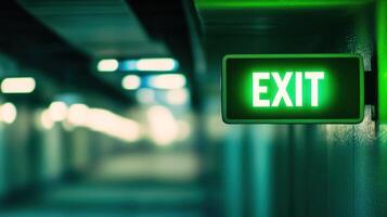 A glowing green exit sign illuminating a dim hallway. photo