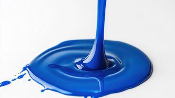 A vibrant blue liquid paint pooling on a white surface. photo
