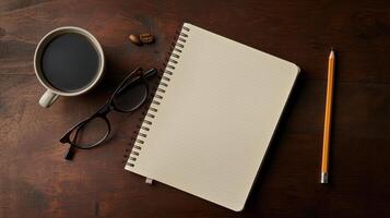 Blank notebook, pencil, coffee cup, and glasses on table photo