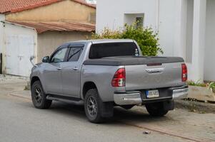 Gaziveren Cyprus -17.03.2025 Silver pickup truck parked on a quiet street under a cloudy sky in a small town setting photo