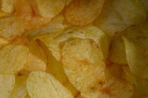 Crunchy golden potato chips scattered in a bowl create a tempting snack experience at any gathering photo