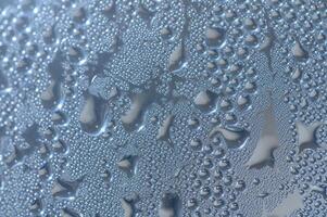 Raindrops dance on a window glass, creating a mesmerizing pattern under soft indoor lighting photo
