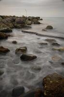 Calm waters dance with mist over rocky shoreline at dusk by the tranquil coast photo