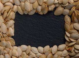 Creative display of pumpkin seeds arranged in a frame on a slate background for autumn festivities photo