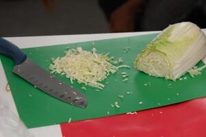 Chopping fresh cabbage on a vibrant green cutting board in a cozy kitchen setting photo