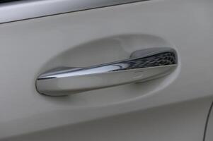 Close-up of a shiny vehicle door handle showcasing modern design and sleek finishing under soft natural light in a suburban setting photo
