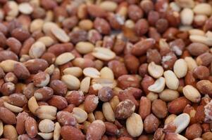 Varied textures and colors of peanuts spread across a market table in a vibrant setting photo