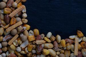 Colorful assortment of mixed nuts and snacks arranged artistically on a dark background, showcasing their textures and shapes photo