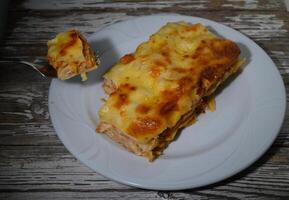Delightful layers of cheesy chicken lasagna served on a rustic wooden table at sunset photo