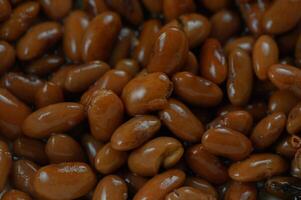 Rich and glossy brown beans nestled together, showcasing their natural sheen and earthy tones under soft lighting photo