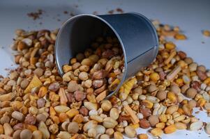 Colorful assortment of nuts spills from tin container creating a vibrant snack display on a bright surface photo