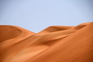 A large sand dune in the desert with a blue sky photo