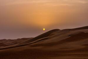 A man is walking in the desert at sunset photo