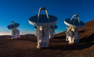 Four large telescopes sitting on top of a hill photo
