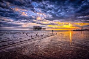 The sun sets over the beach and pier photo
