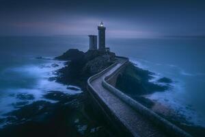 A lighthouse sits on top of a rocky cliff photo