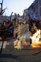 A man dressed in a deer costume is walking in front of a fire photo