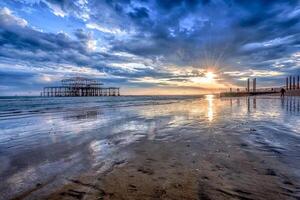 The sun is setting over the west pier in brighton photo