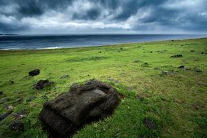 A large rock sits in the grass on a green field photo