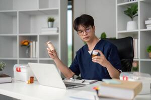 Medication Review and Study. A medical student analyzing prescription bottles while studying medicine at a desk. photo