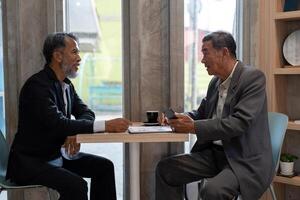Exchange of Ideas and Insights. Two senior men discussing business strategies over coffee in a cafe. photo