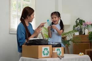 Recycling and Parent-Child Learning. A mother teaches her daughter about recycling by sorting different materials together, highlighting eco-friendly practices. photo