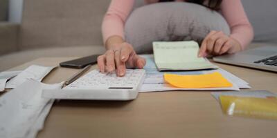 Calculating Expenses and Financial Management. A woman keeping track of financial documents and receipts while using a calculator. photo