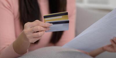 Credit Management and Finance Strategy. Close-up of a woman holding multiple credit cards and reviewing paperwork as part of her financial strategy. photo