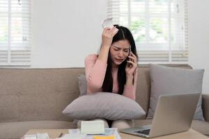 Stress and Financial Issues. A woman expresses frustration on the phone while dealing with financial concerns, highlighting tension in financial management. photo