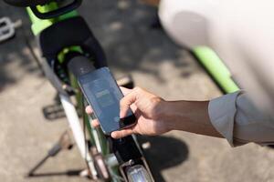 Smart Cycling and Modern Commuting. A young man uses his smartphone while preparing to ride a green bicycle, highlighting the functions of smart commuting. photo