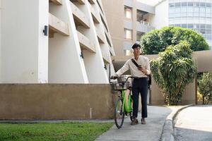Urban Cycling and Technology. A young man checks his phone while standing by his bicycle. photo
