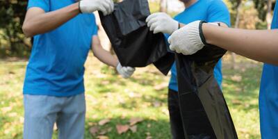 Community Service and Cleanliness. A group of volunteers collaborates hand-in-hand to gather trash during a park cleanup. photo