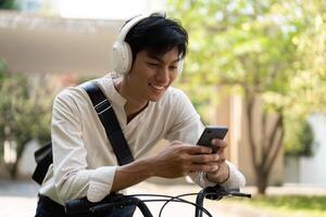 Joyful Biking and Engagement. A young man smiling while using his smartphone during a leisurely bike ride. photo