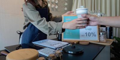 Sustainable Consumer Choices and Rewards. A customer receiving a discount for using their own cup at a cafe. photo