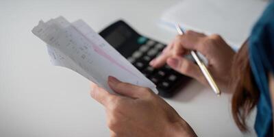 Expense Tracking and Calculating Savings. An individual reviewing receipts while calculating expenses with a calculator. photo