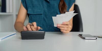 Smart Budgeting and Expense Management. A woman focused on organizing her finances using a calculator and handling receipts. photo